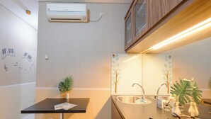 A compact kitchen with a built-in sink, a small countertop, and a wall-mounted air conditioner.