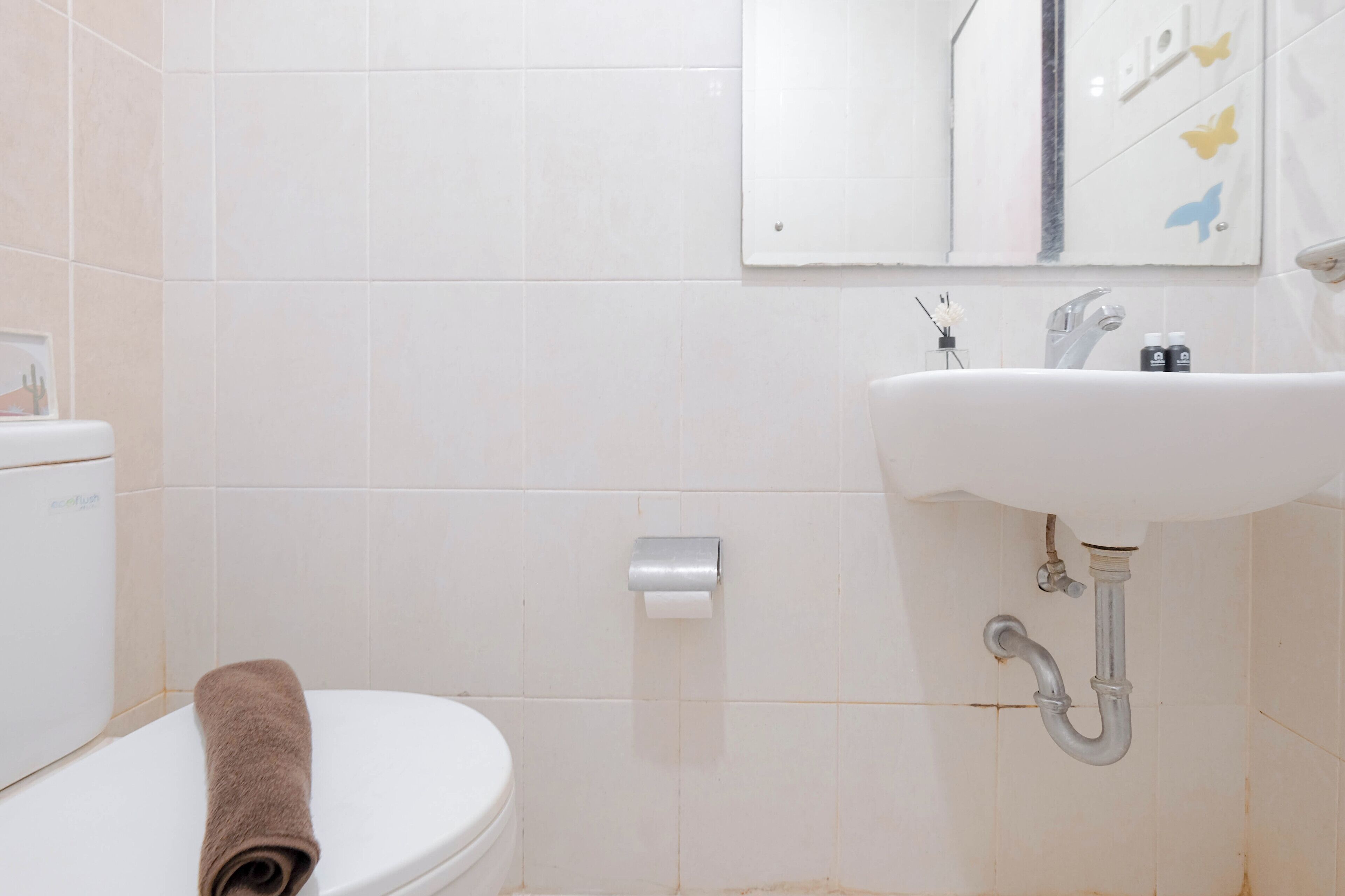 Et badeværelse med toilet, håndvask og et håndklæde på gulvet.