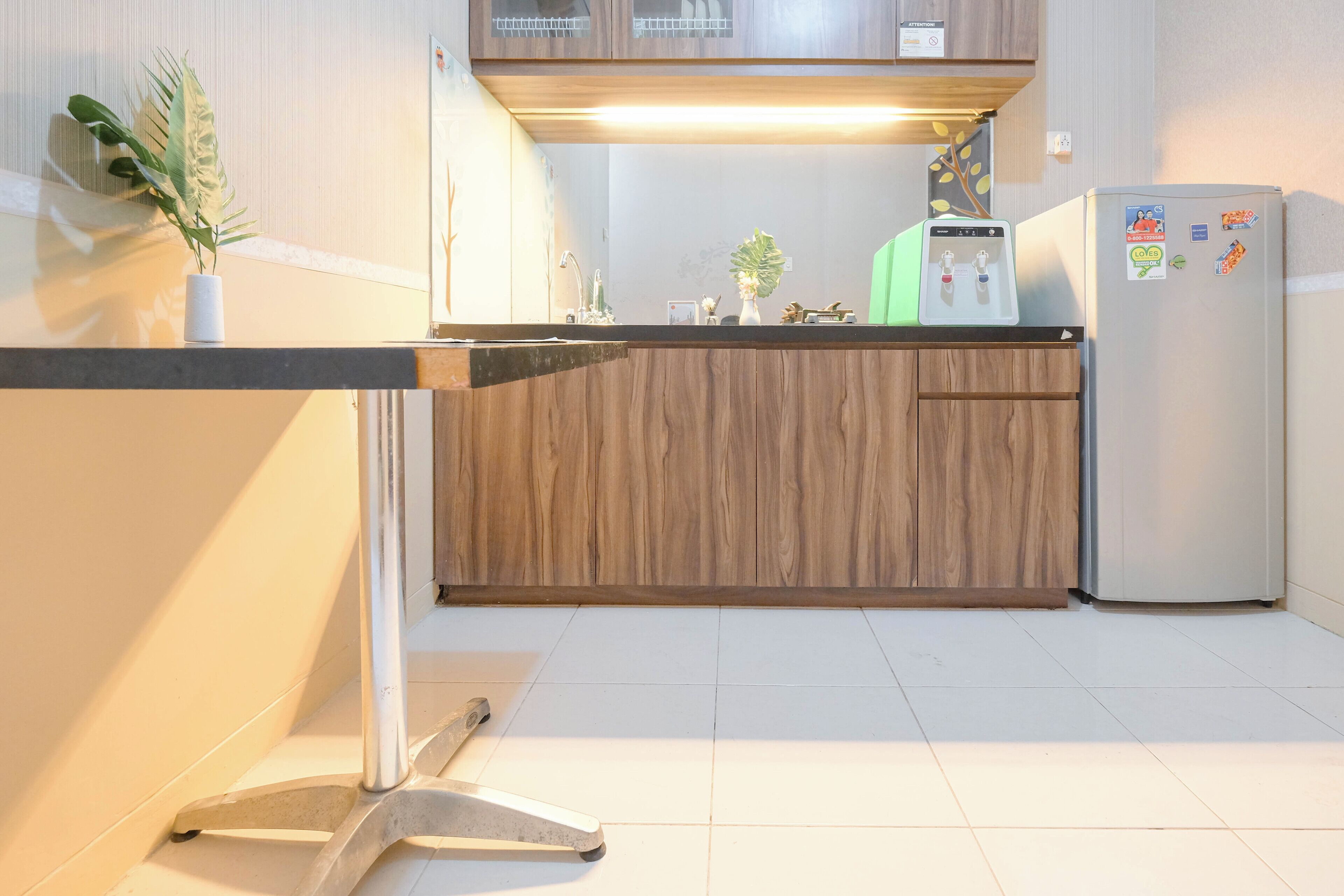 A modern kitchen with wooden cabinets, a stainless steel refrigerator, and a small island with a sink.