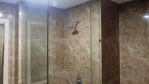 A glass-enclosed shower with a handheld showerhead and a wall-mounted faucet. - Spacious Studio Room Apartment at Grand Sungkono Lagoon (Surabaya)