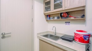A kitchen with a sink, a rice cooker, and a cabinet with glass doors. - Comfort and Strategic Studio Meikarta Apartment (Cikarang)