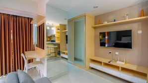A modern living room with a large flat-screen TV, a sofa, and a dining area with a table and chairs.