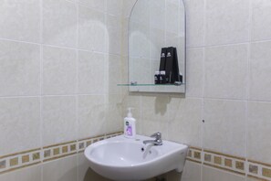 A bathroom with a white sink, a mirror, and a shelf with toiletries.