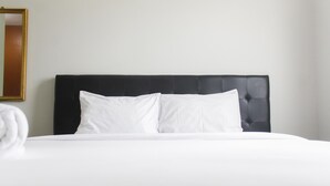 A neatly made bed with white linens and a black headboard in a hotel room. - Comfort and Stylish 2BR at Grand Palace Kemayoran Apartment (Jakarta)