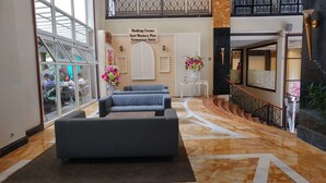 A hotel lobby with a seating area, a staircase, and a sign indicating the location as Wedding Corner at Kemayoran Hotel. - Comfort and Stylish 2BR at Grand Palace Kemayoran Apartment (Jakarta)