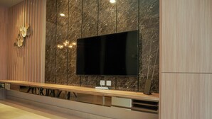 Una cocina moderna con una televisión de pantalla plana grande montada en un salpicadero de mármol, armarios de madera y una encimera integrada con un lavamanos.