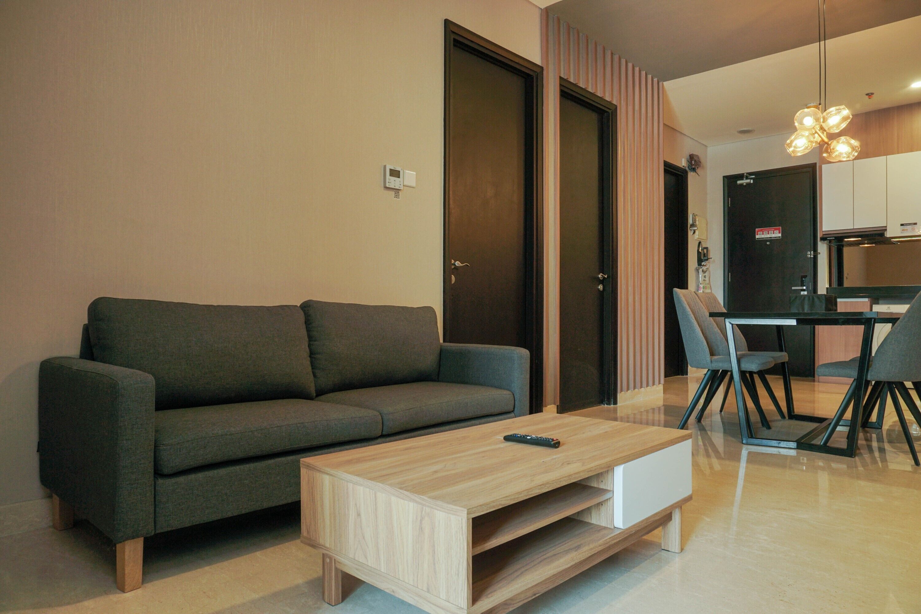 A modern living room with a sofa, a coffee table, and a dining area with chairs and a table.