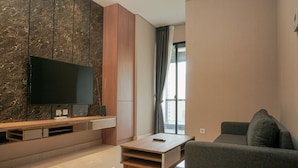 Una sala de estar moderna con un televisor de pantalla plana montado en una pared de mármol, un mueble de madera, un sofá gris y una mesa de centro.