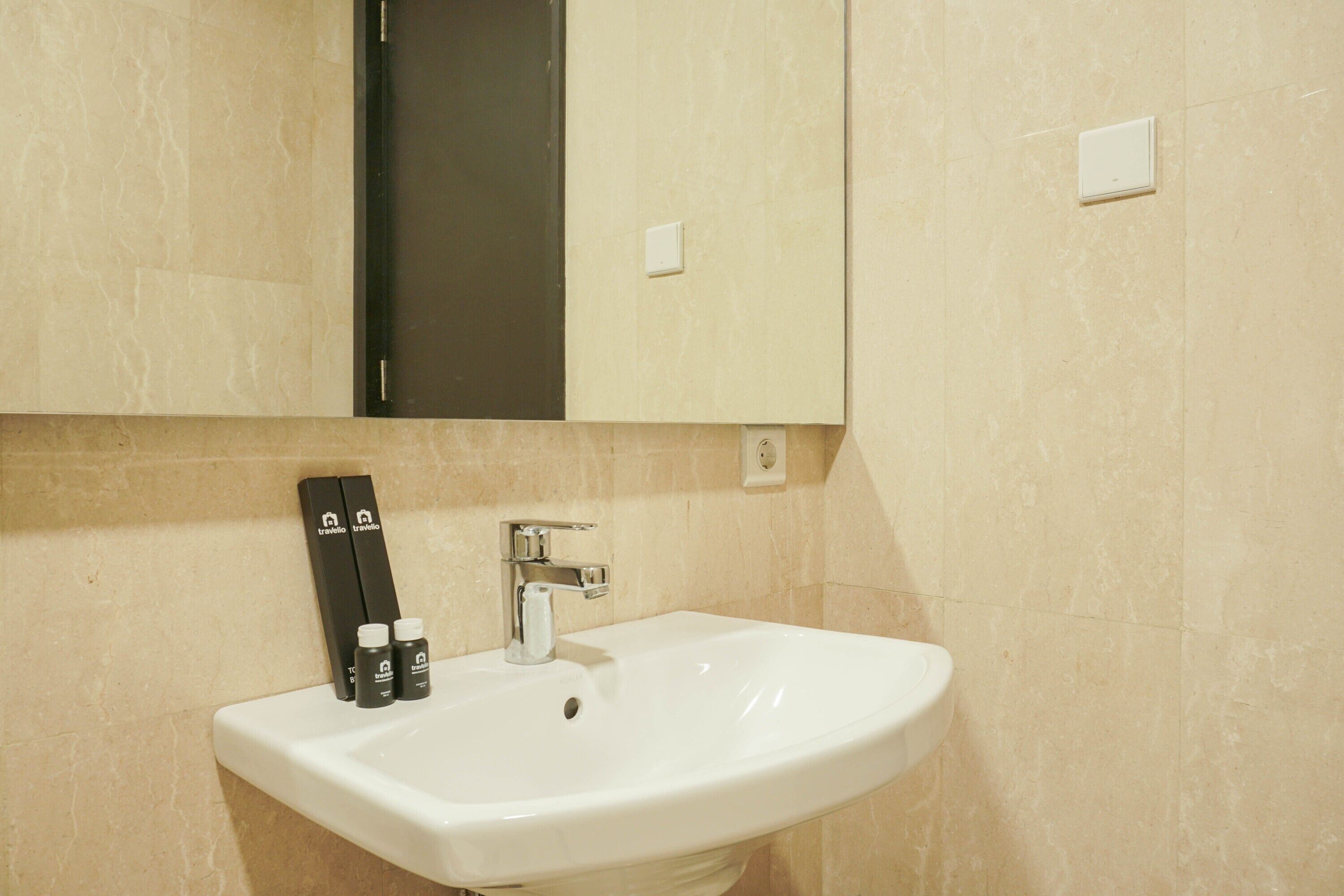 A bathroom with a white sink, a mirror above it, and two toiletries on the sink's edge.