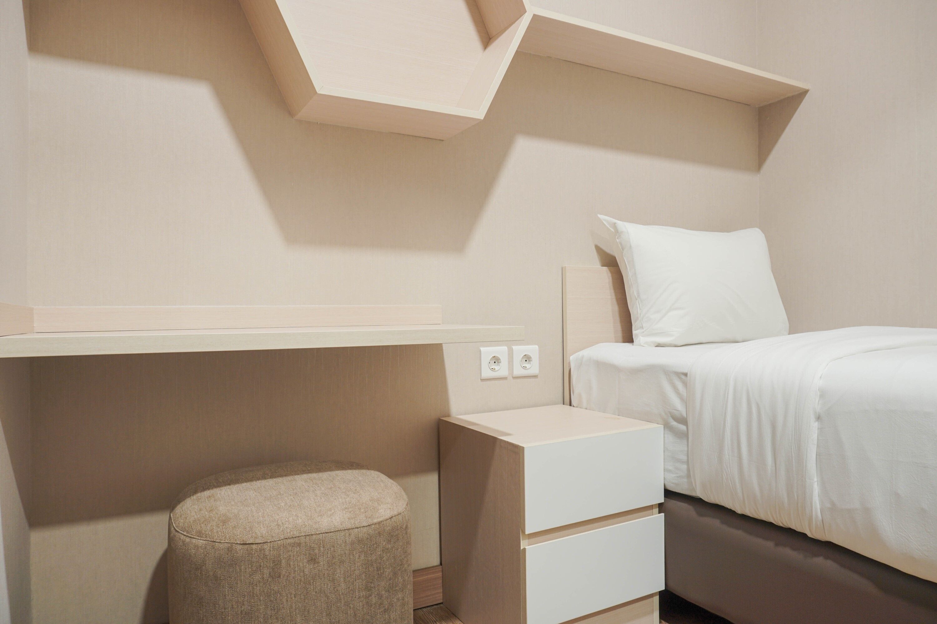 Una camera da letto con un letto, un comodino e un poggiapiedi.