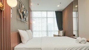 Una habitación de hotel con una cama grande, una silla, un escritorio y una ventana con cortinas.