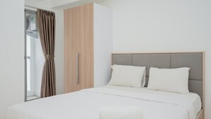 A neatly made bed with a white duvet, a grey headboard, and two white pillows. - Cozy Living 2BR at M-Town Residence Apartment (Gading Serpong)