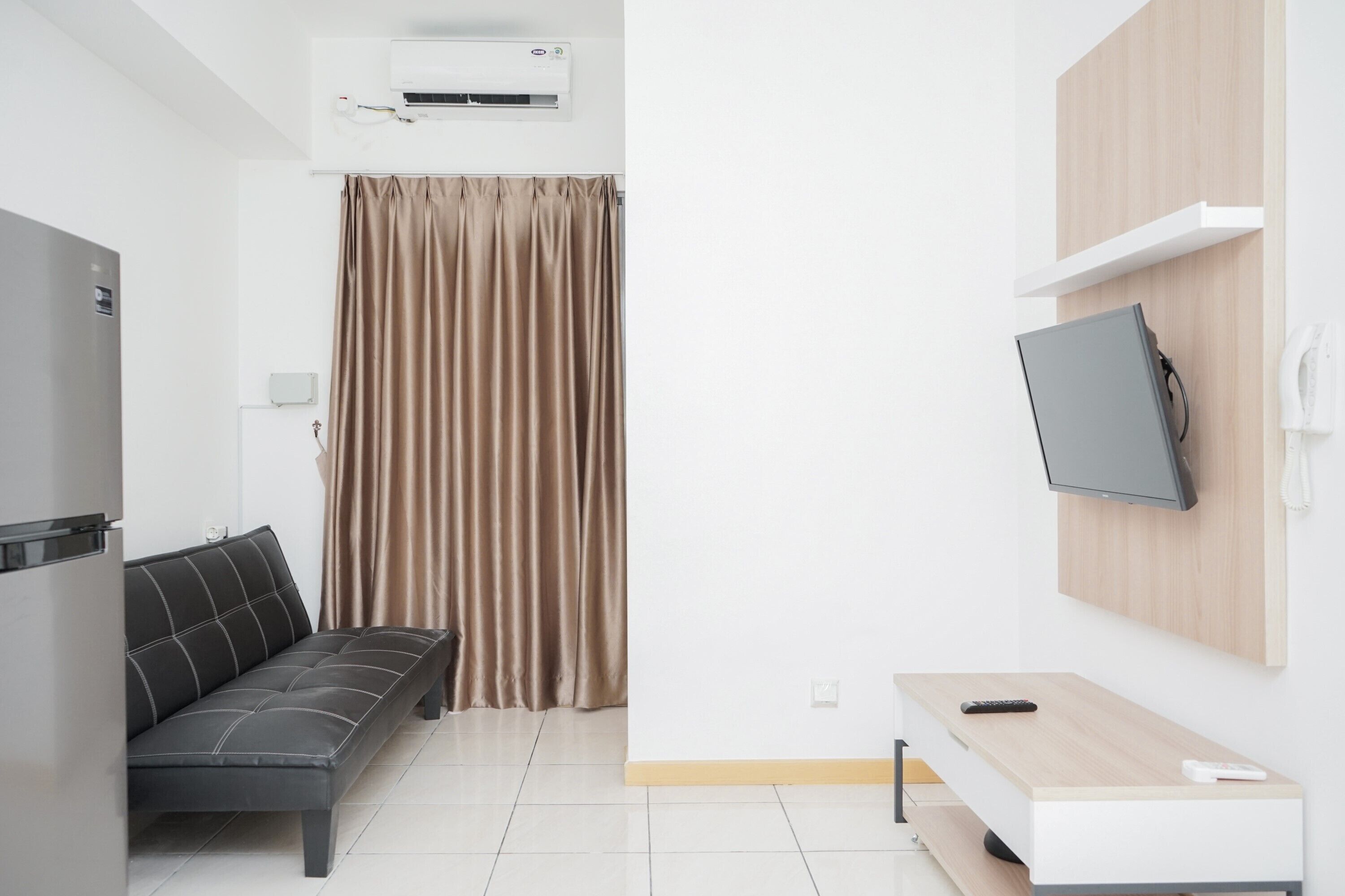 Uma sala de estar moderna com um sofá, uma TV fixada na parede e uma TV de tela plana sobre um suporte.