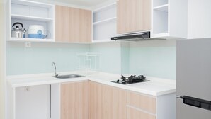 A modern kitchen with white countertops, wooden cabinets, a built-in stove, and a stainless steel kettle. - Cozy Living 2BR at M-Town Residence Apartment (Gading Serpong)
