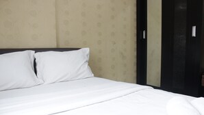 A hotel room with a neatly made bed, a dark headboard, and a patterned wallpaper. - Strategic & Relaxing 2BR at Gateway Apartment Ahmad Yani Cicadas (Bandung)