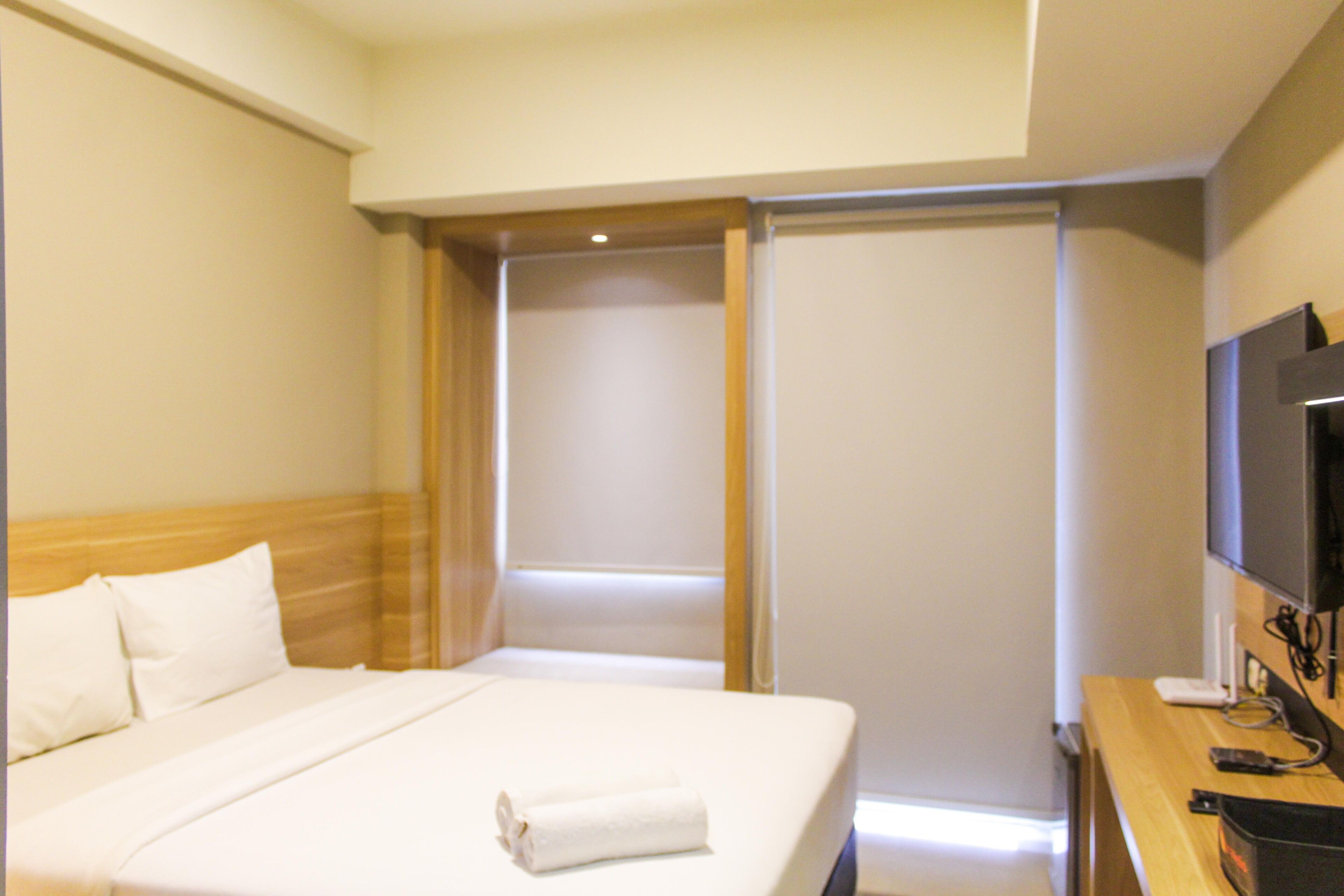 Ein Hotelzimmer mit Bett, Fernseher und Schreibtisch.