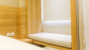 A compact room with a built-in bench, wooden paneling, and a white wall. - Cozy and Comfortable Studio (No Kitchen) Apartment at Mustika Golf Residence (Cikarang)