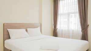 A neatly made bed with white linens and a folded white towel, a wooden headboard, and sheer curtains with a brown tie-back. - Wonderful 1BR at Silkwood Apartment (Tangerang)