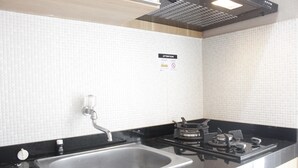 A kitchen with a stainless steel sink, black countertop, and a gas stove. - Favorable 1BR Apartment at Parahyangan Residence near UNPAR (Bandung)
