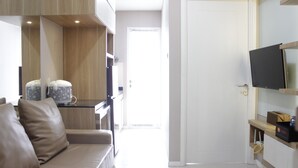 A modern living room with a sofa, a coffee table, and a flat-screen TV mounted on the wall. - Favorable 1BR Apartment at Parahyangan Residence near UNPAR (Bandung)