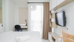 Ein Hotelzimmer mit einem Bett, einem Schreibtisch, einem Sessel, einem Fernseher und einem Fenster mit Vorhängen.