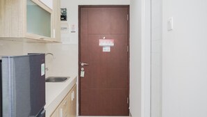 Eine schmale Küche mit Kühlschrank, Spüle und Holzschrank.