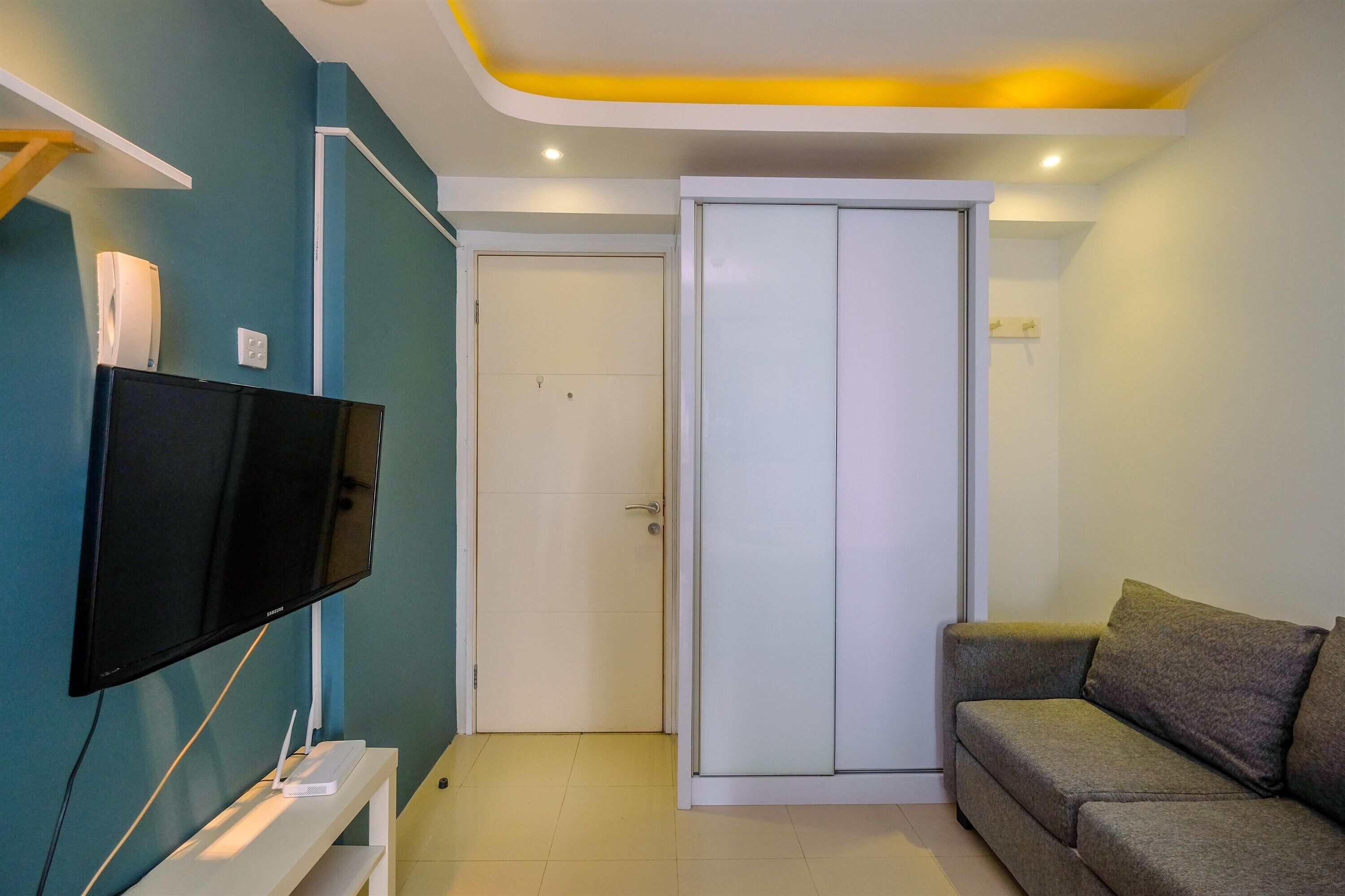 A modern living room with a flat-screen TV, a sofa, and a sliding door closet.