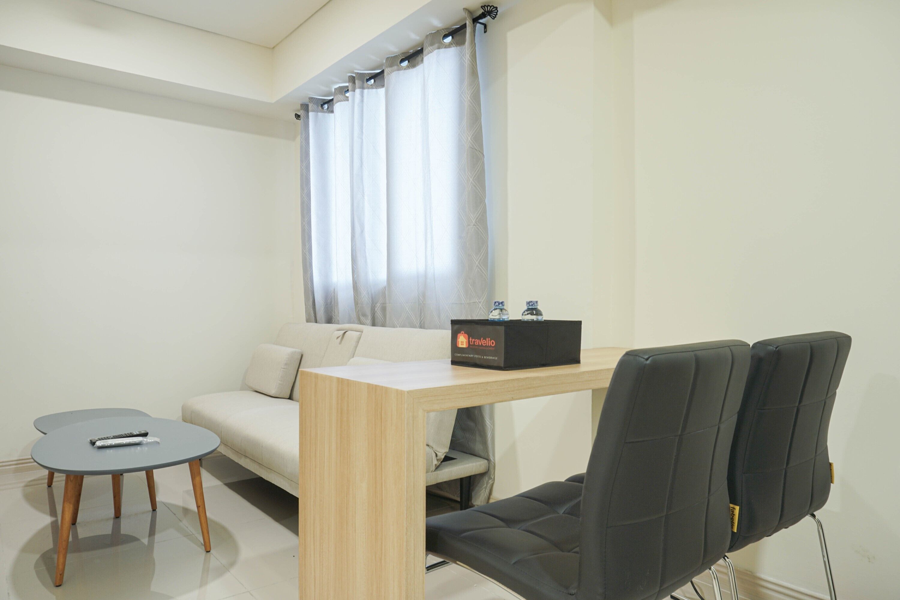 Una habitación moderna con una mesa de madera, una silla negra, un sofá y una mesita redonda.