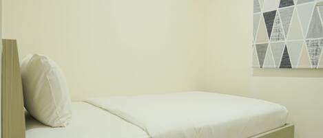 Una cama individual con estructura y cabecera de madera, un cajón de noche y una ventana con diseño geométrico instalada en la pared.