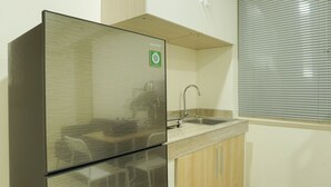 Une cuisine de taille réduite, dotée d’un réfrigérateur en acier inoxydable, d’un évier et de meubles de rangement en bois.