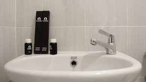 A white sink with a chrome faucet, two toothbrushes, and two bottles of toothpaste.