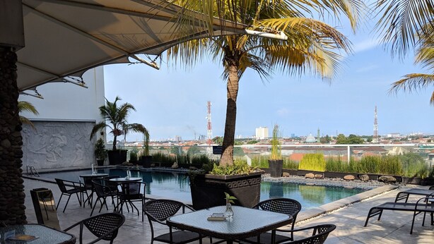 Zona de piscina exterior con asientos y vistas del horizonte de la ciudad.