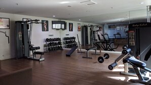 Un gimnasio con varios equipos de ejercicio, como mancuernas, una prensa de banca y una cinta de correr.