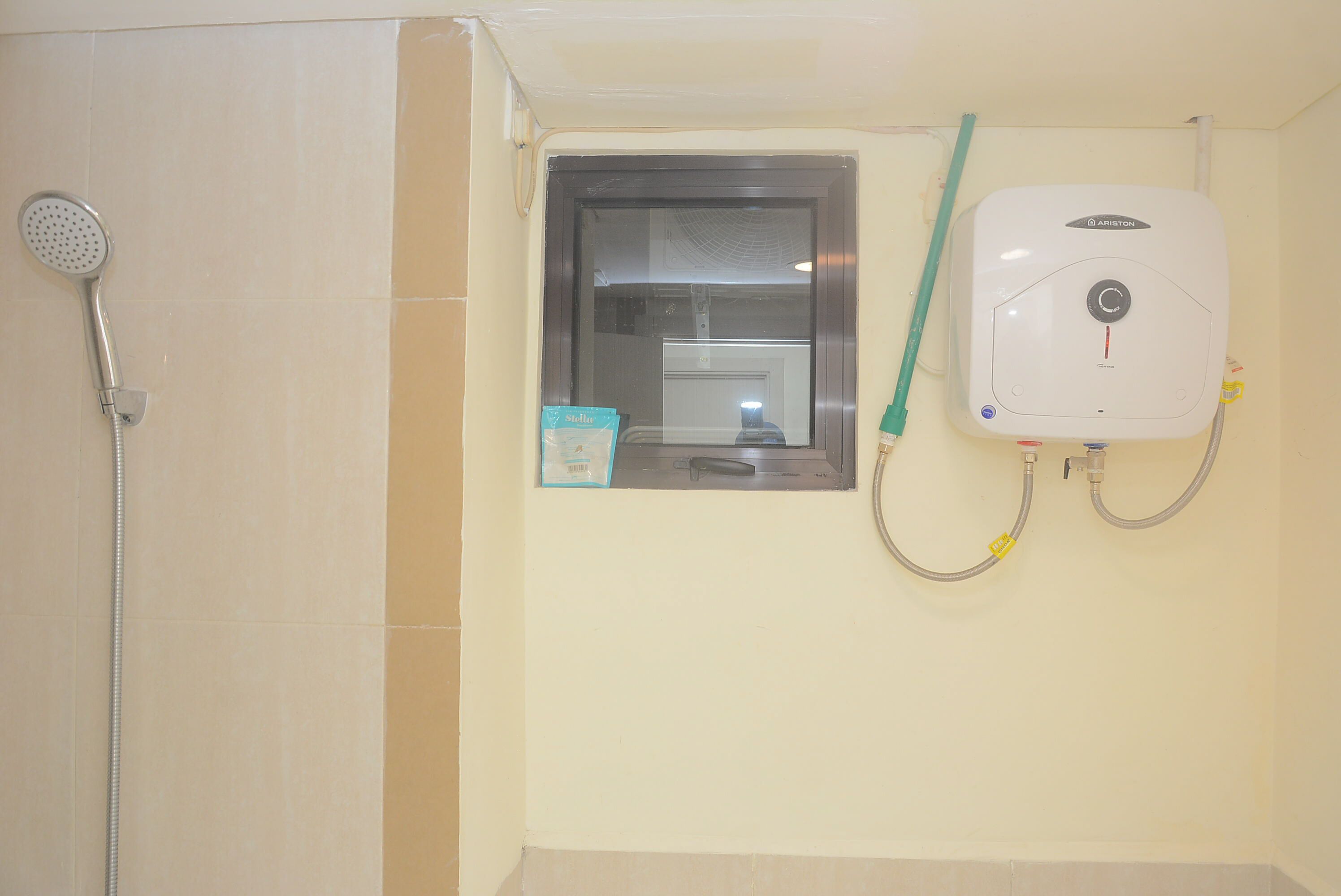A bathroom with a shower, a window, and a water heater.