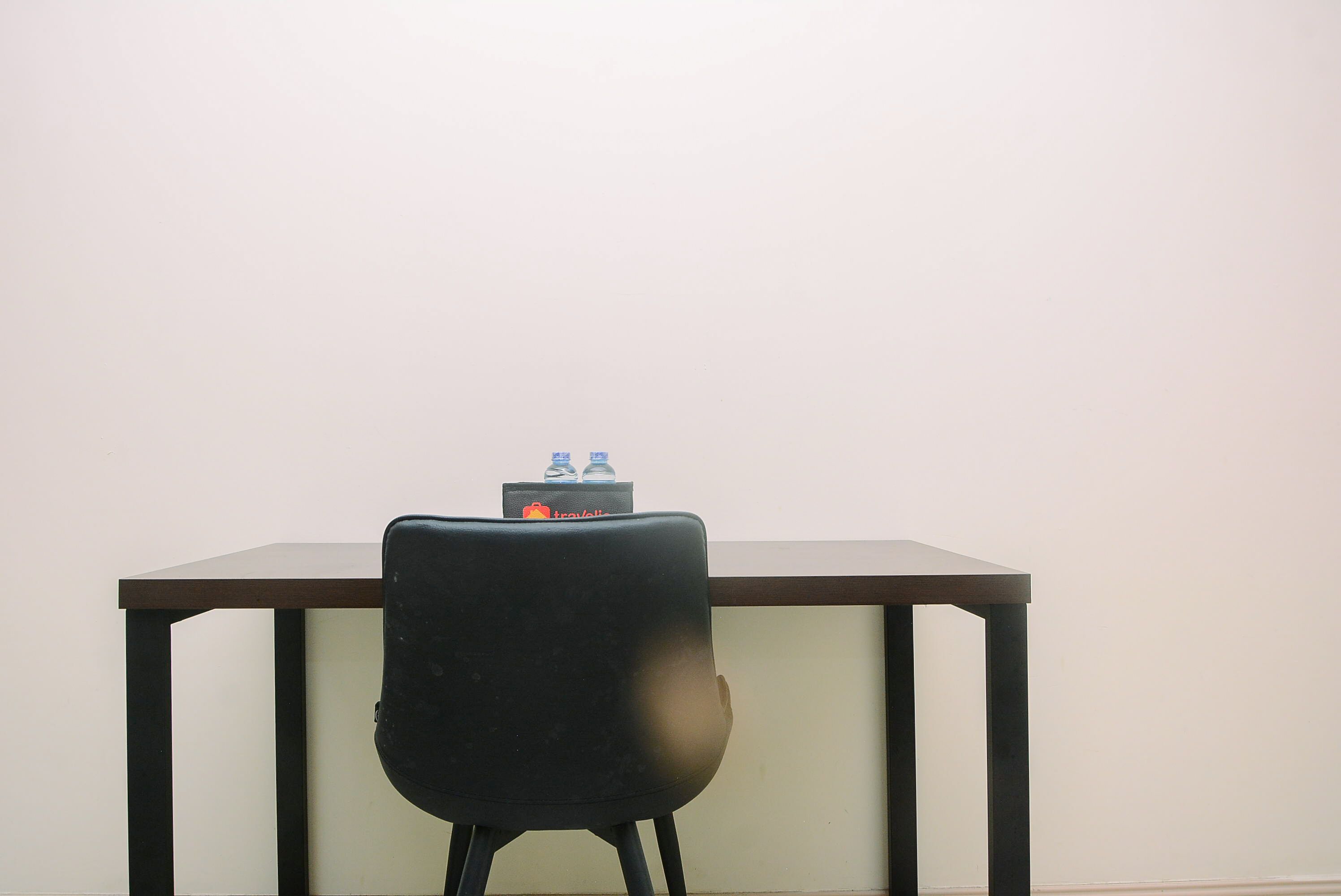 A chair facing a table with a water bottle on it.
