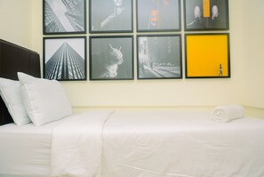 Une chambre d’hôtel avec un lit, des oreillers, une couverture blanche et un mur orné de tableaux.
