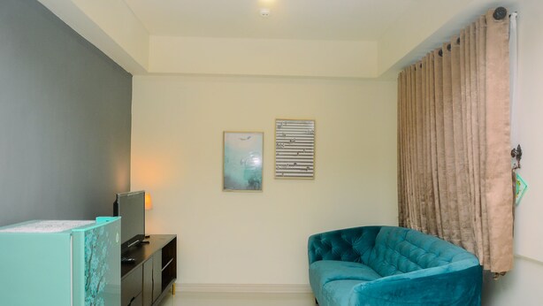 Un salon avec un canapé de couleur turquoise, un téléviseur posé sur un meuble et deux œuvres d’art encadrées accrochées au mur.