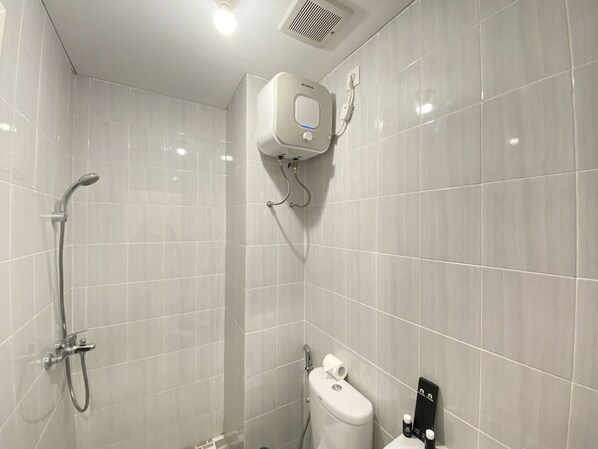 A bathroom with a shower, toilet, and a hand dryer.