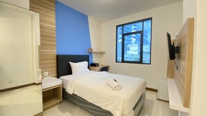 Una habitación de hotel moderna con una cama grande, una mesita de noche, un televisor montado en la pared y una ventana con vistas a la ciudad.