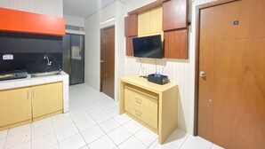 Uma cozinha moderna com forno embutido, pia e micro-ondas. Há um armário de madeira com uma televisão montada em cima.