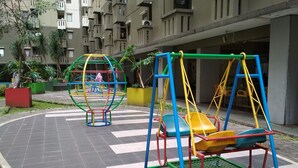 Um parquinho com balanços e estrutura de escalada em ambiente urbano.