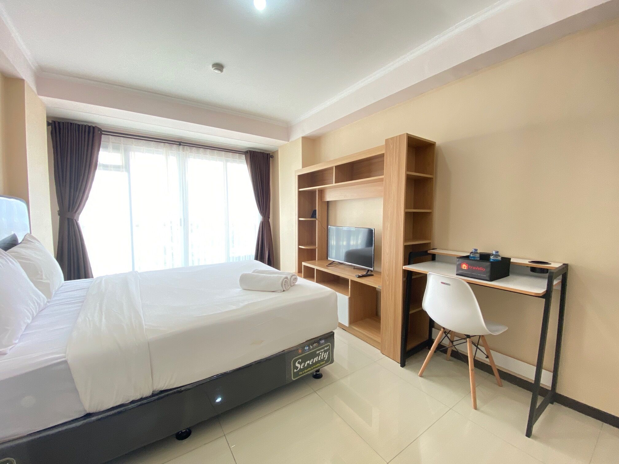 Une chambre d’hôtel avec un lit, un bureau équipé d’un ordinateur, une télévision et une chaise.