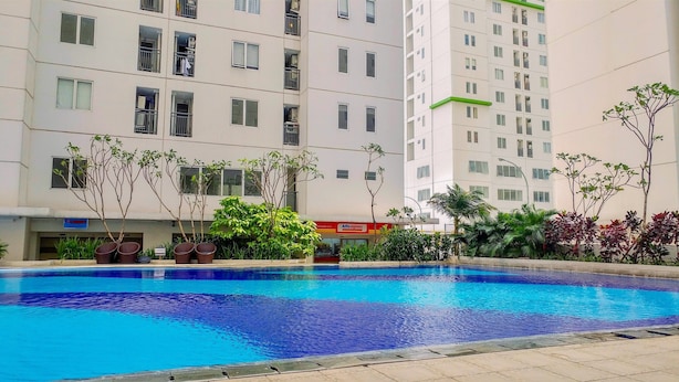 A swimming pool surrounded by a multi-story residential building with balconies and a visible shop sign.