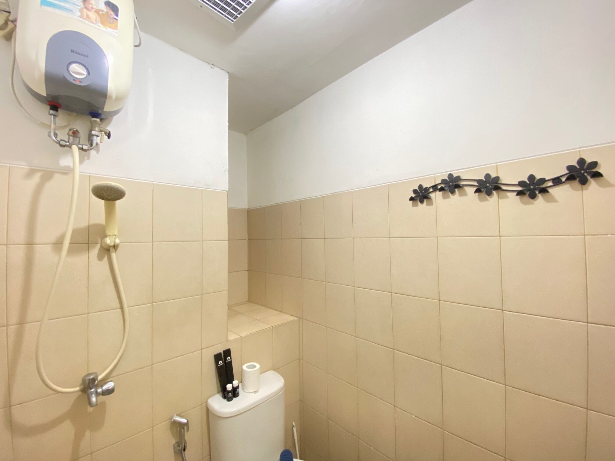 Une salle de bain équipée d’une douche, de toilettes et d’un sèche-mains fixé au mur.
