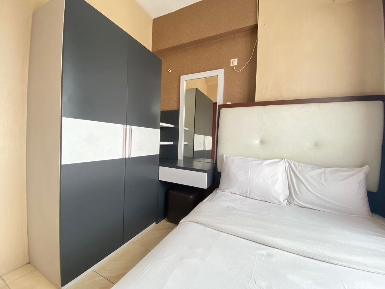A bedroom with a bed, a wardrobe, and a mirror.
