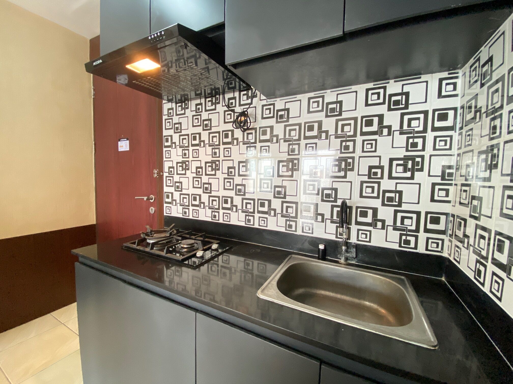 Une cuisine moderne avec un dosseret à motifs noir et blanc, un évier en acier inoxydable et une cuisinière à gaz.