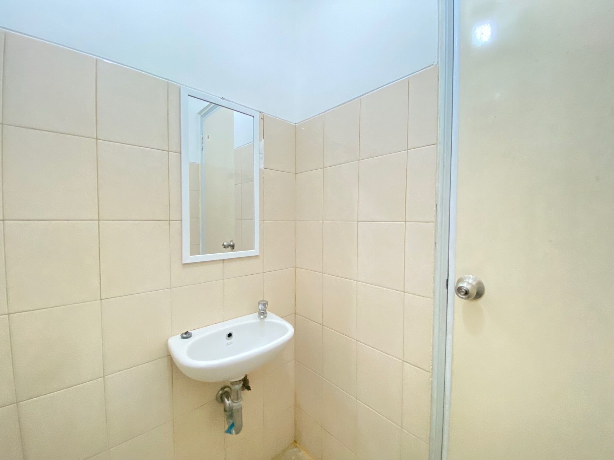Casa de banho com uma pia branca, um espelho e uma porta de chuveiro.