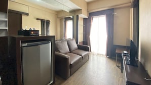 A compact living area with a kitchenette, a sofa, a TV, and a dining table. - Spacious 1BR at Tamansari Panoramic Apartment near Metro Indah Mall (Bandung)