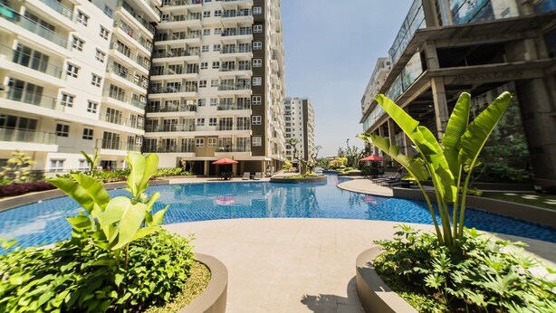 A modern residential building with a central swimming pool surrounded by lush greenery.