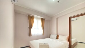 A hotel room with a large bed, a mirror, and a window with curtains.